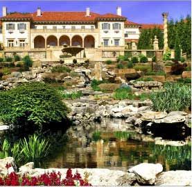 There is a large house in the background with a pond in front of it.