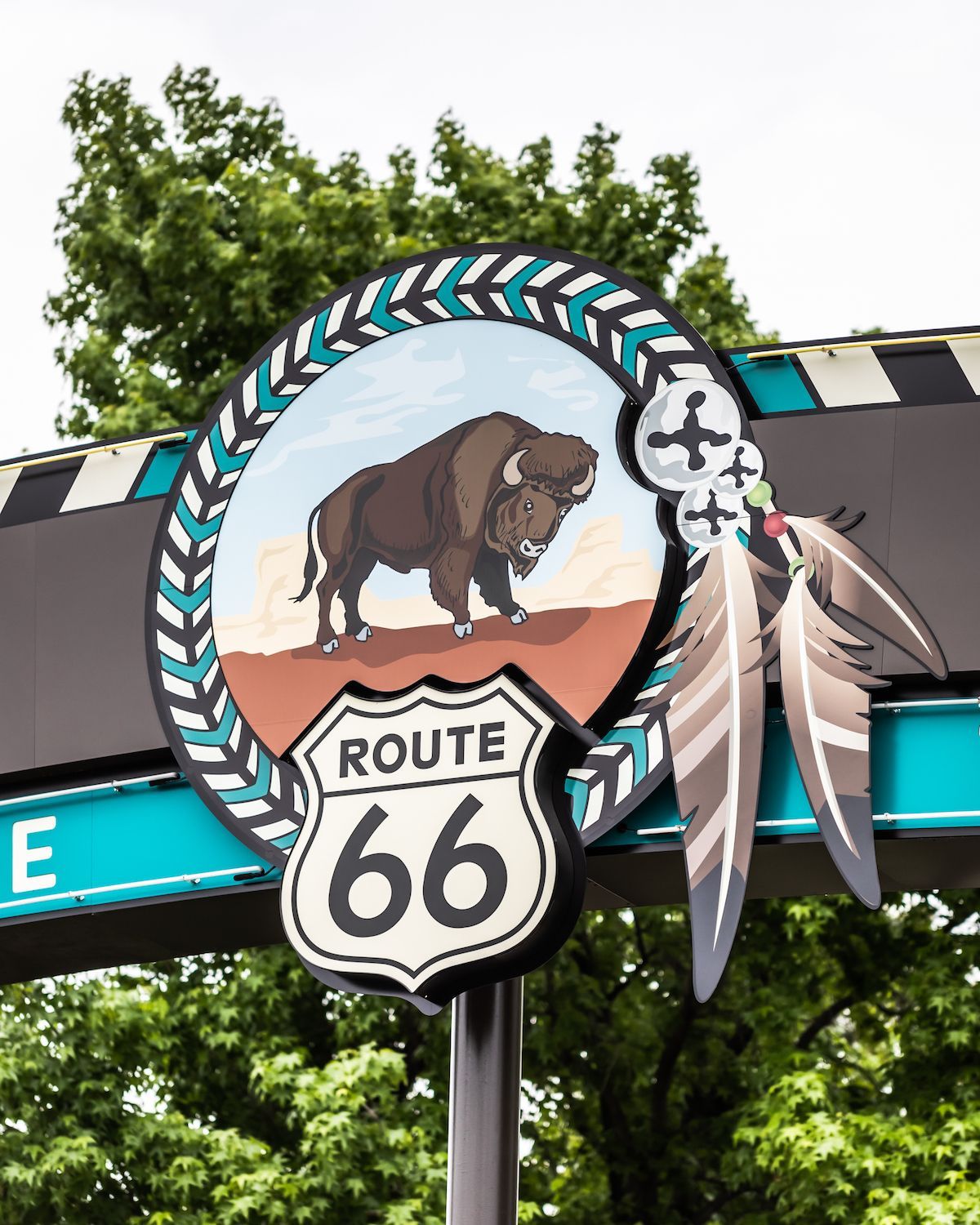 A route 66 sign with a bison and feathers on it