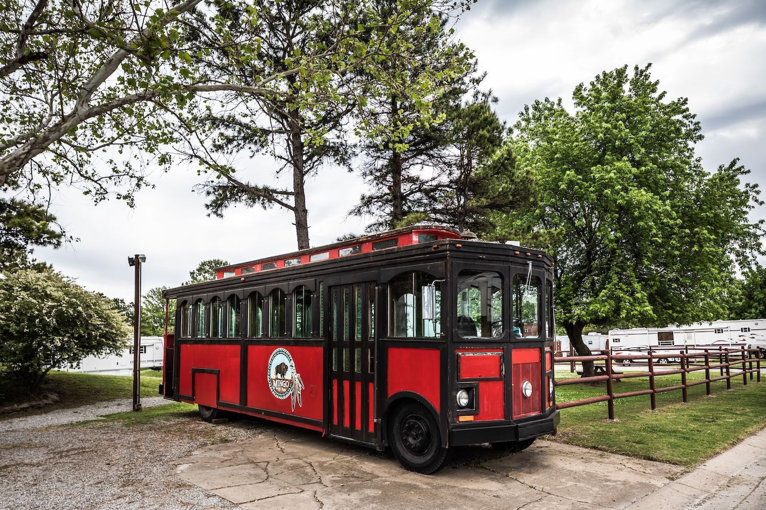A red and black bus is parked in a parking lot.