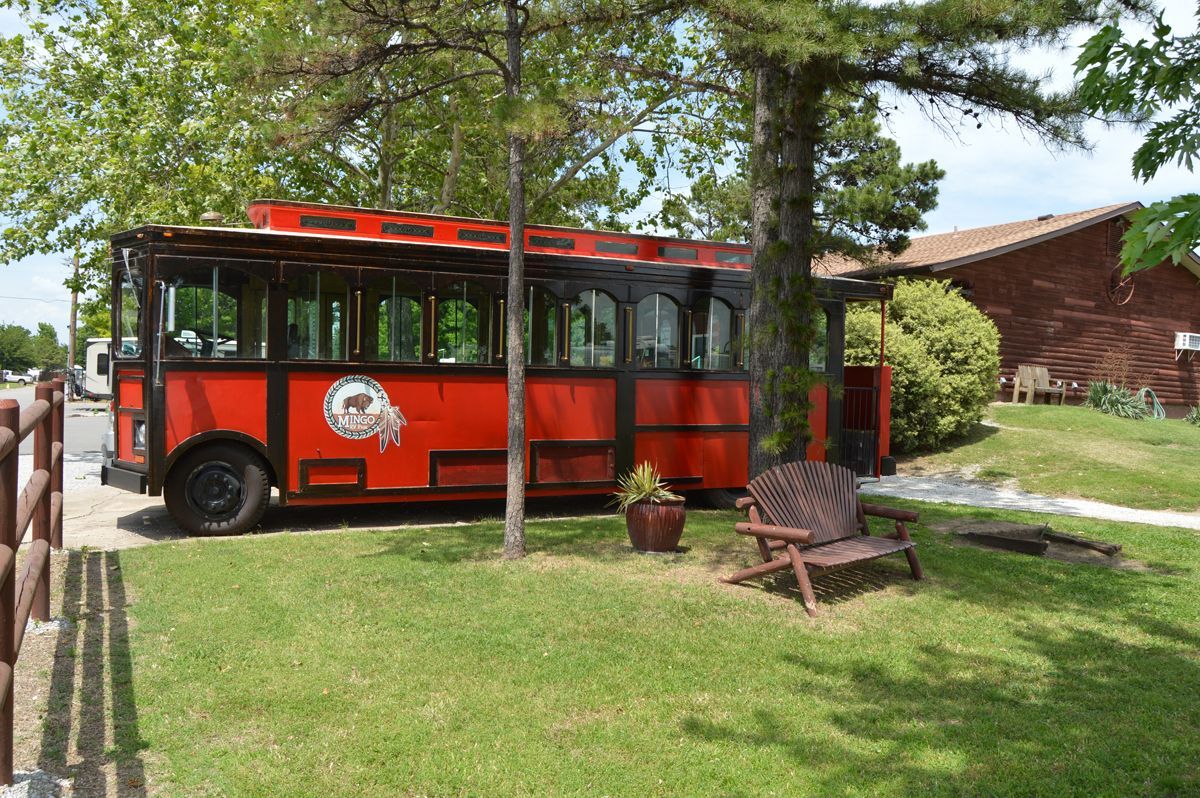 A red bus is parked in the grass in front of a house.