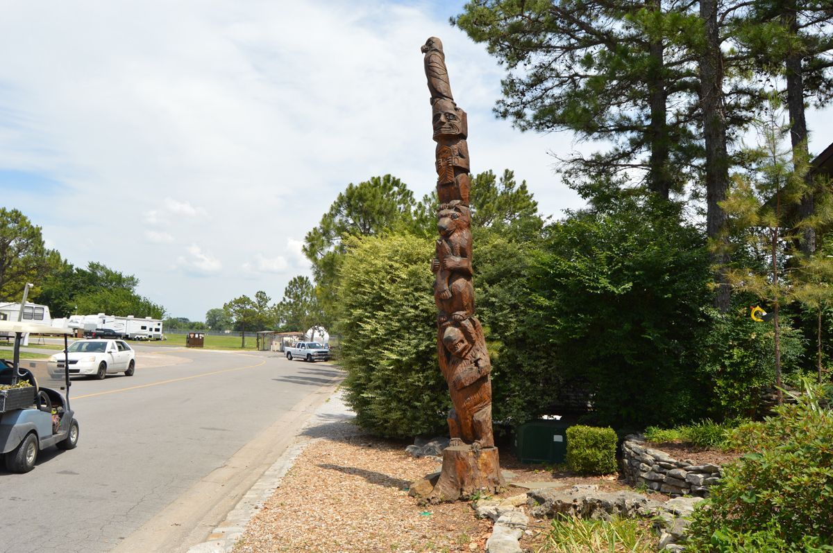 A totem pole is sitting in the middle of a parking lot.