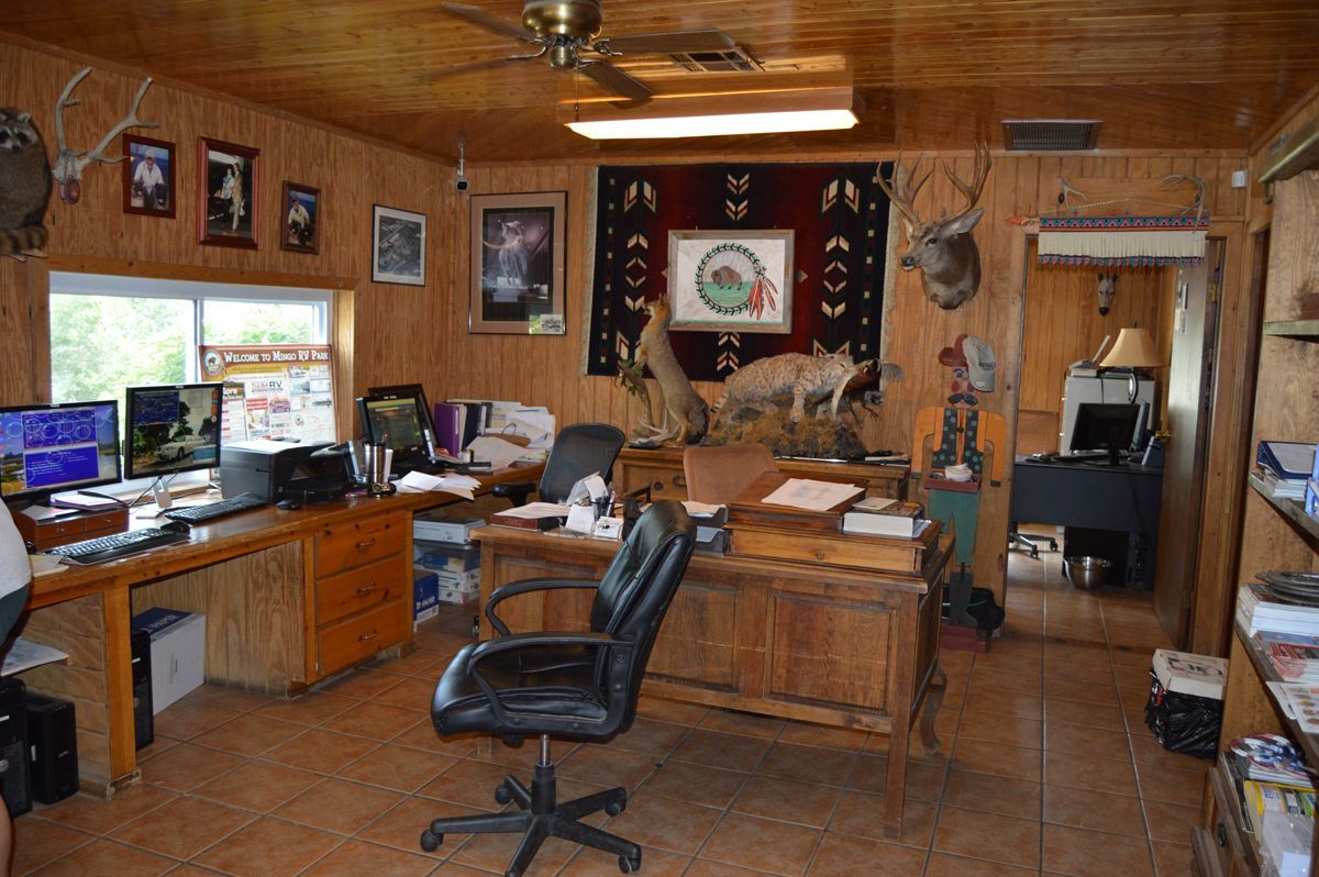 A man is standing in a room with a desk and chair.