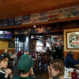Busy sports bar interior with patrons seated at tables and TV screens above the counter.