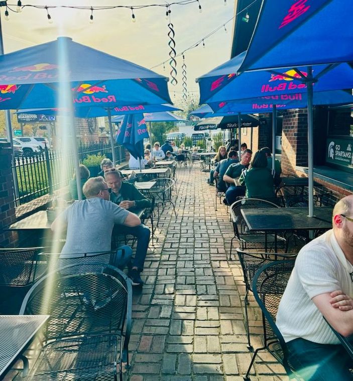 A person is sitting at a table with a bowl of chips and a glass of beer.