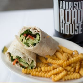 Wrap sandwich with crinkle-cut fries on a plate beside a Harrison Roadhouse cup