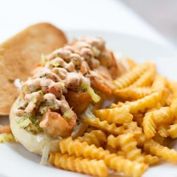 Hot dog topped with relish and diced toppings, served with crinkle-cut fries on a white plate