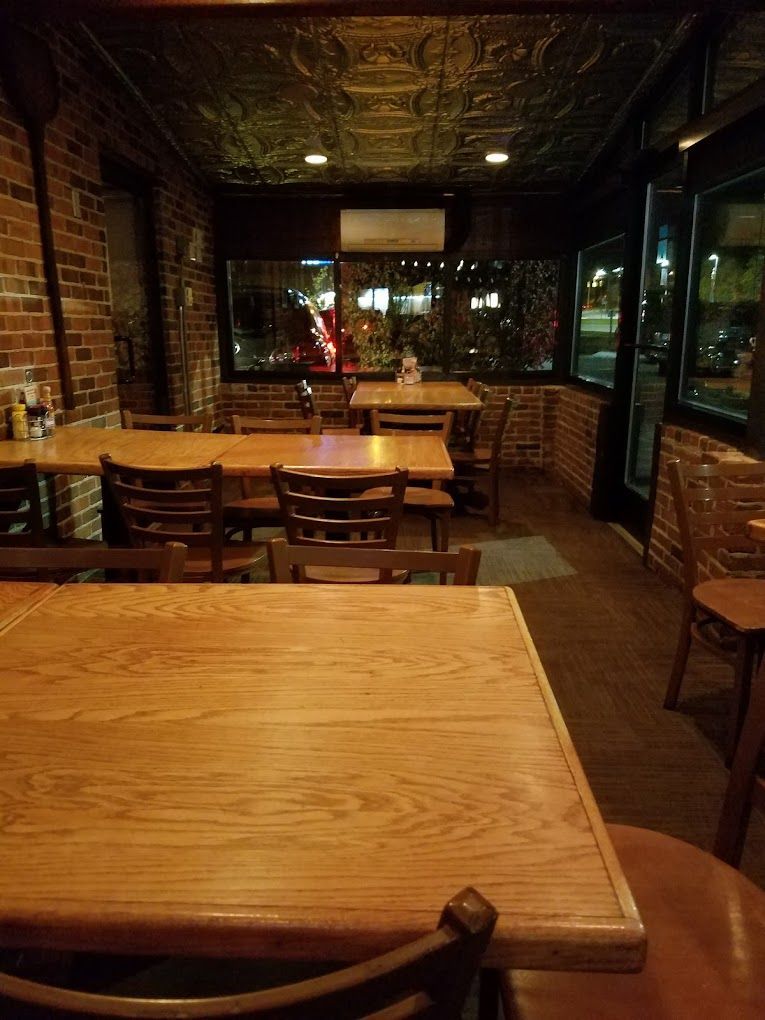 A restaurant with wooden tables and chairs and a brick wall.