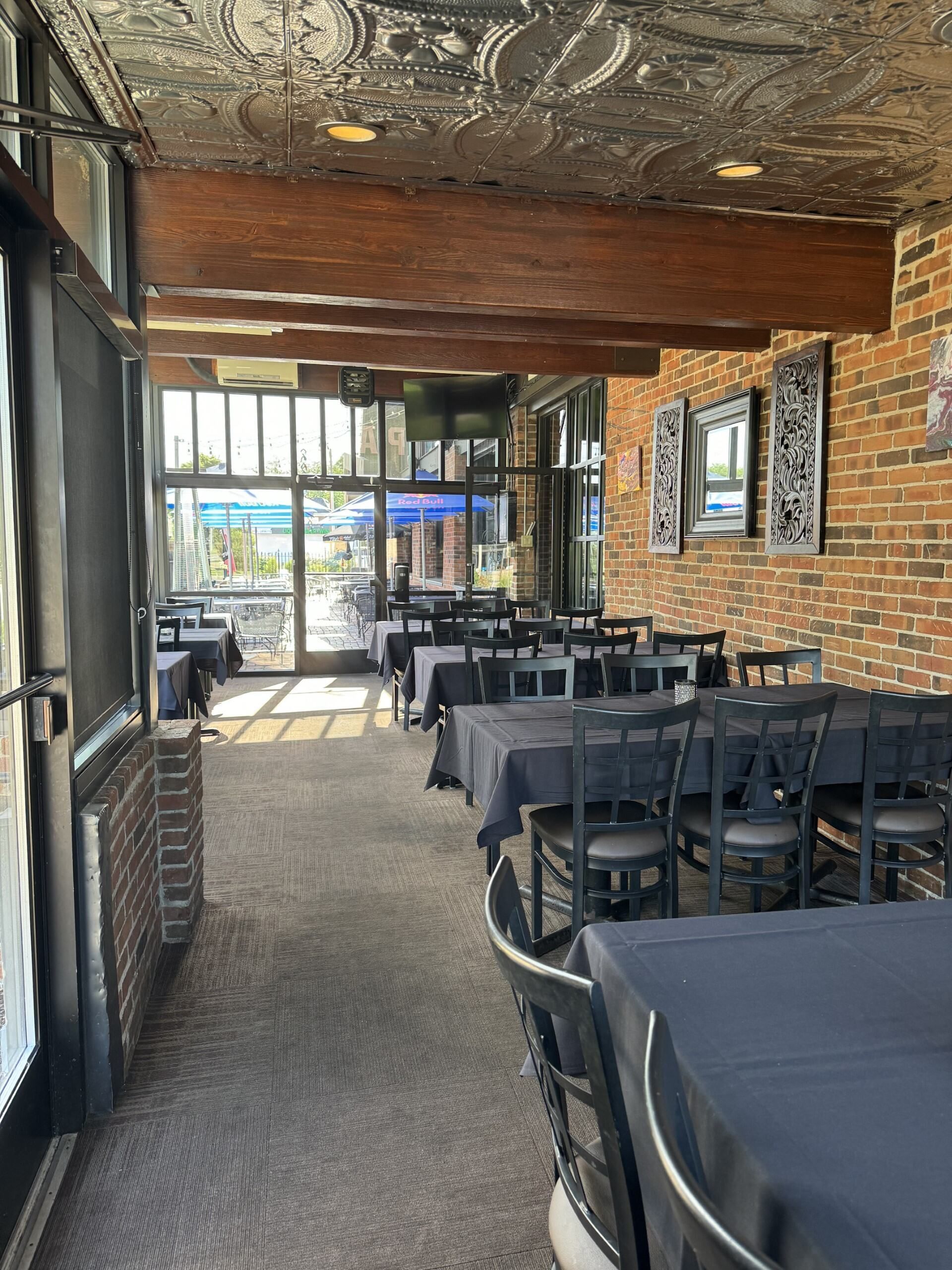 A restaurant with tables and chairs and a brick wall.