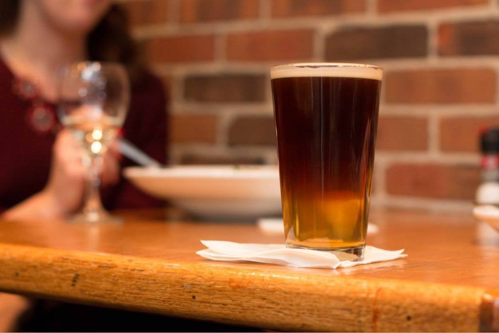 A glass of beer is sitting on a wooden table.