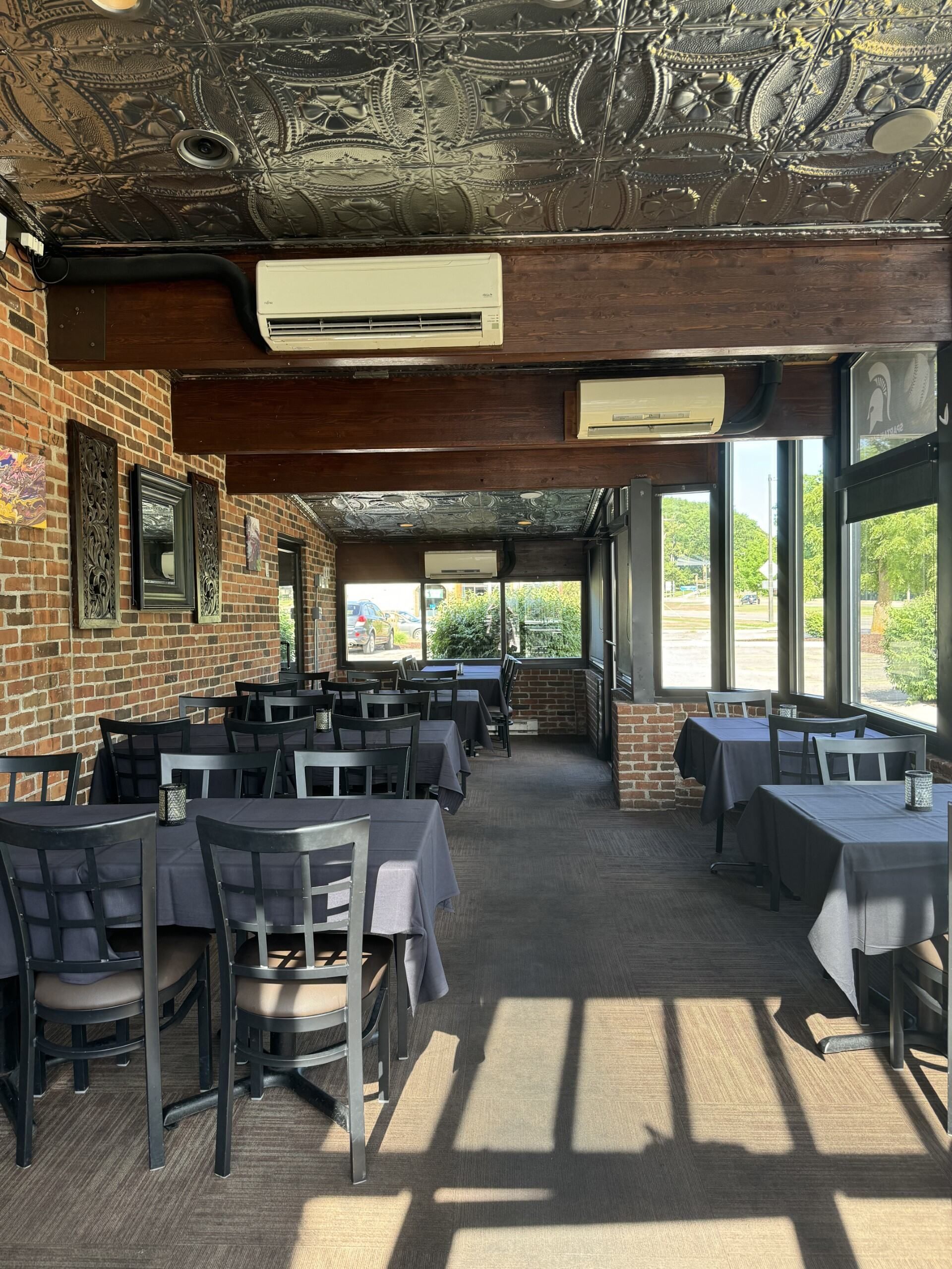A restaurant with tables and chairs and a brick wall.