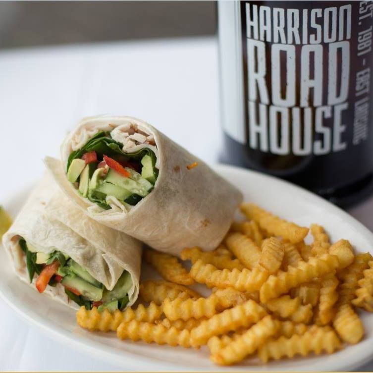 A plate of food with a bottle of harrison road house in the background