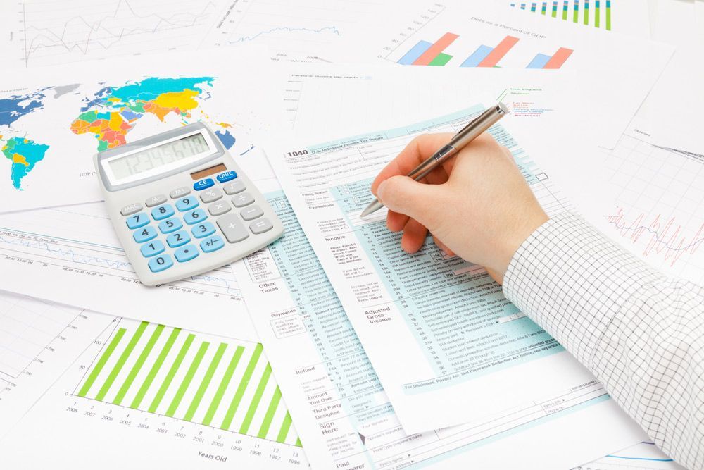 A Calculator and a Hand Holding a Pen Completing a Tax Form — Tax Depreciation Schedule in Grafton, NSW