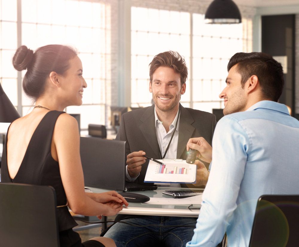 Happy Couple Sitting at a Desk With a Financial Advisor — Property Advisory in Grafton, NSW