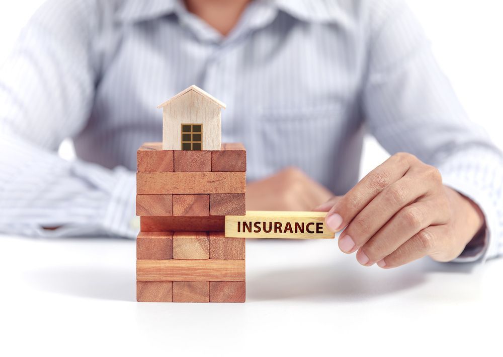 A Hand Pushing Wooden Brick with the Word Insurance on it — Property Insurance in Grafton, NSW