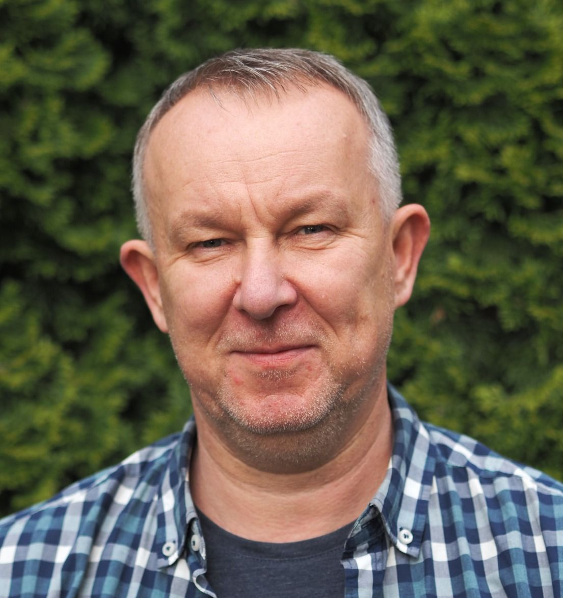 Woman with blonde hair and bangs, wearing a light-colored blazer and gray top, smiling at the camera.