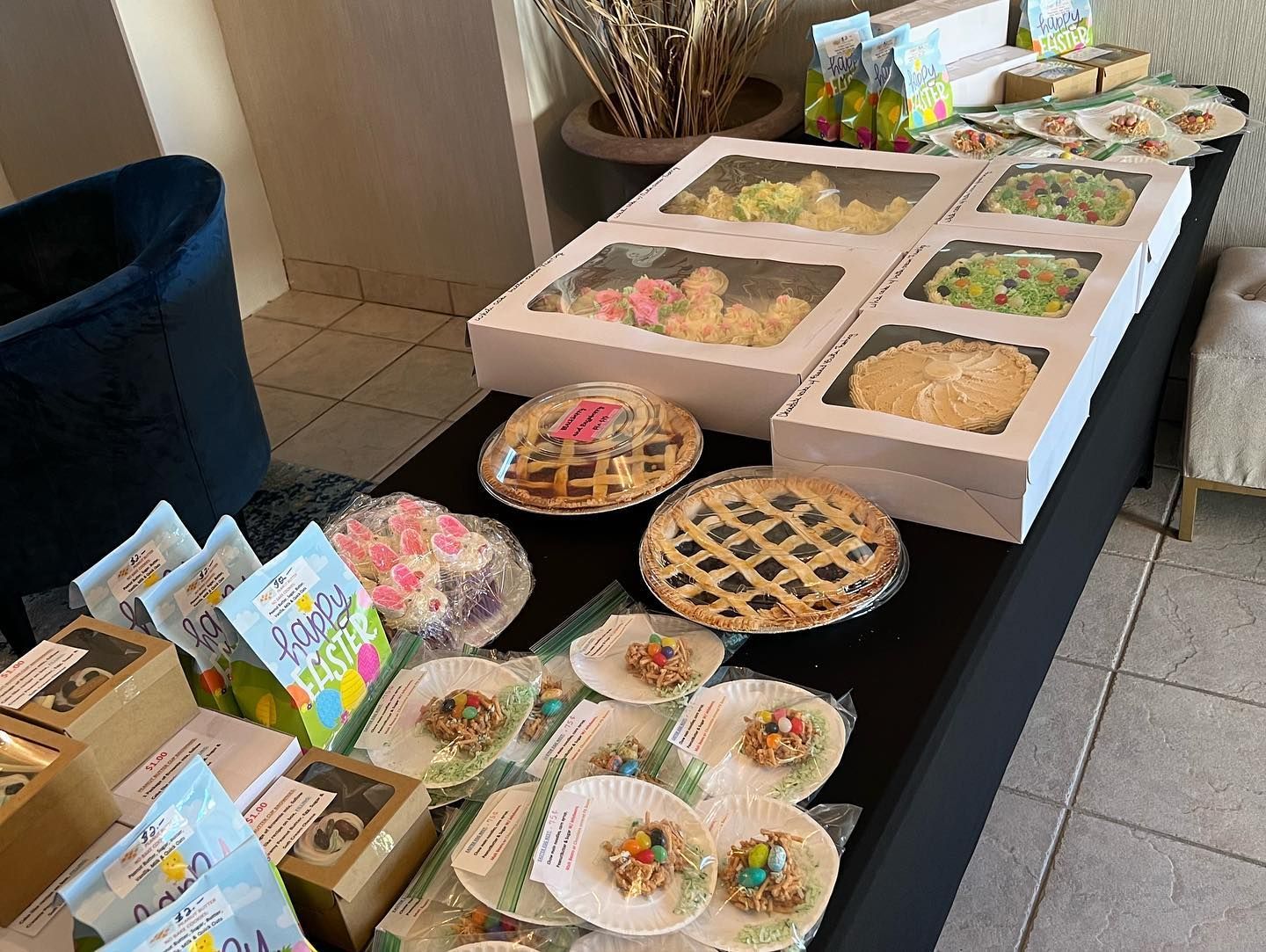 Dessert buffet table with pies, pastries, and boxed treats arranged on a black tablecloth
