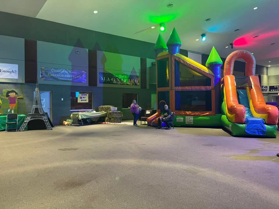 Indoor trampoline and play area with colorful slides, climbing structures, and a few people inside.