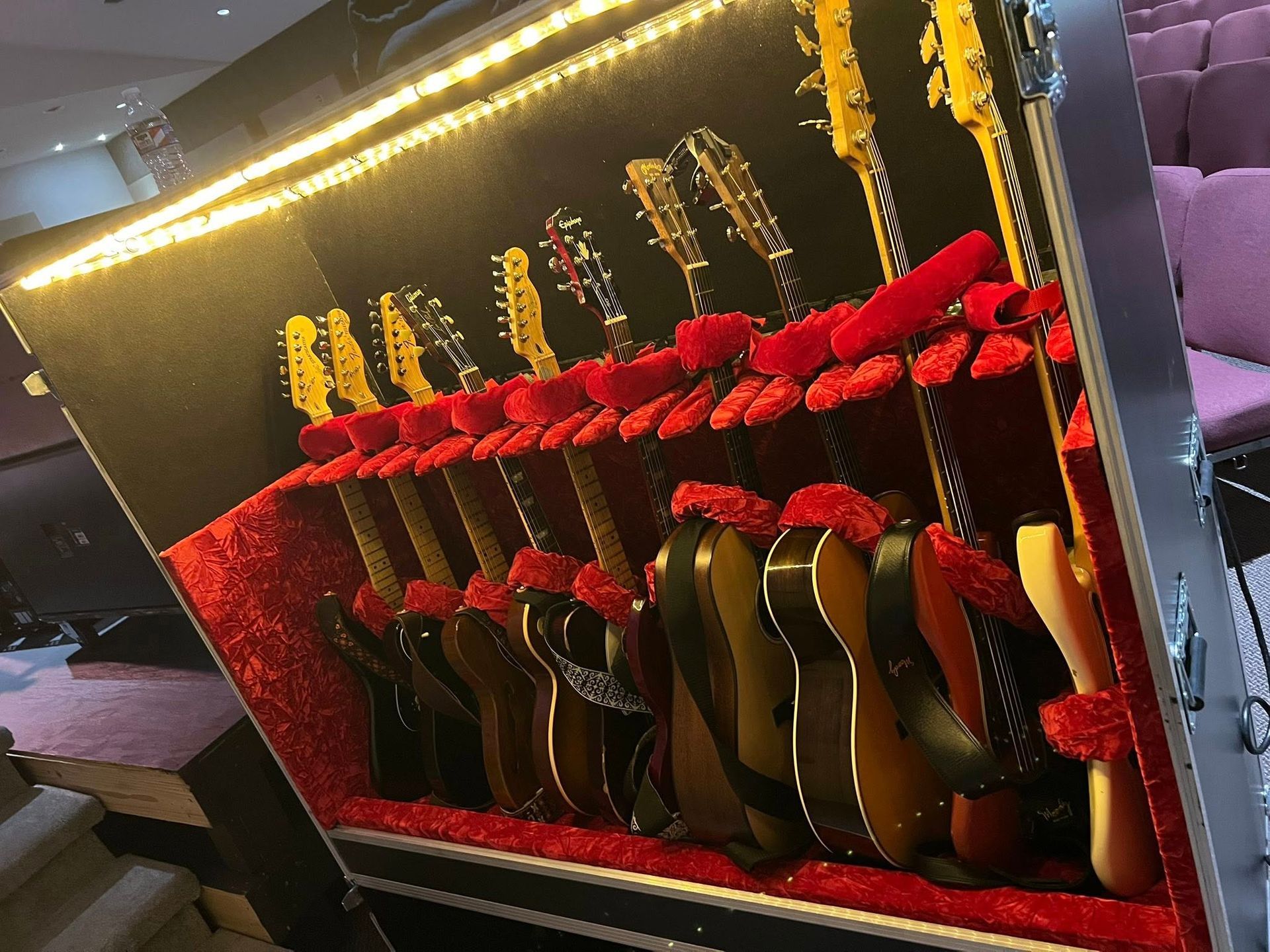 Guitars arranged in a lit display case with red decorations and warm string lights.
