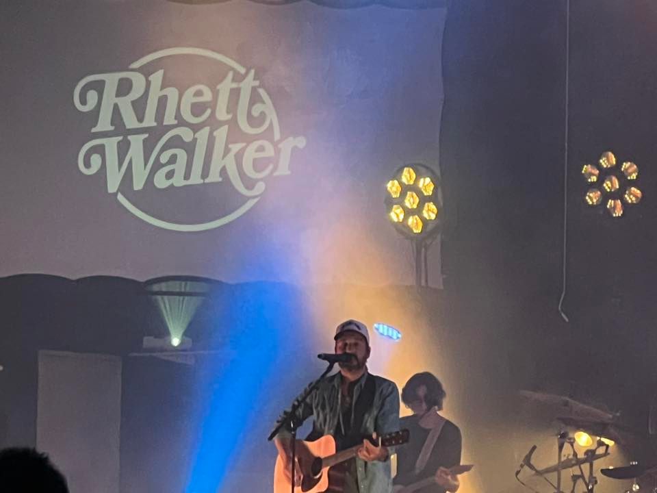 Rhett Walker performing live on stage with guitar under blue and amber lights
