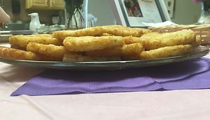 Plate of golden fried sticks on a table with a purple napkin underneath