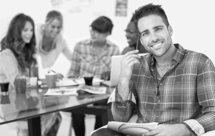 A man in a plaid shirt is sitting in front of a group of people.