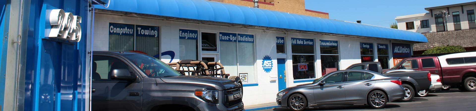 A row of cars are parked in front of a building with a blue awning - A Street Automotive
