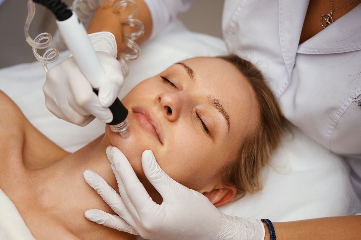 Cosmetic procedure on a woman's face with gloved hands using a treatment device