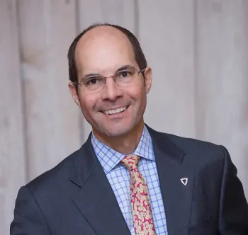 Wills Elliman in a suit and tie is smiling for the camera