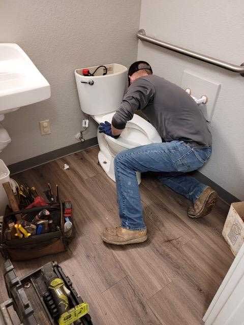 Back-view-of-young-professional-plumber-fixing-sink-in-bathroom