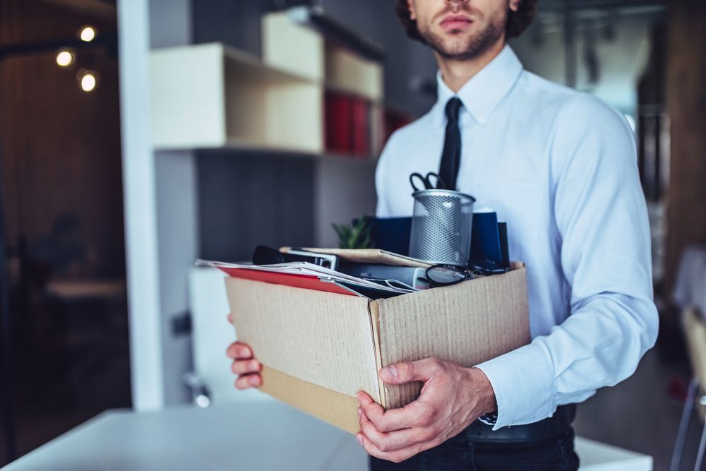 Man Holding a Cardboard Box of Office Belongings in an Office Setting — Bradley Solicitors in Larrakeyah, NT