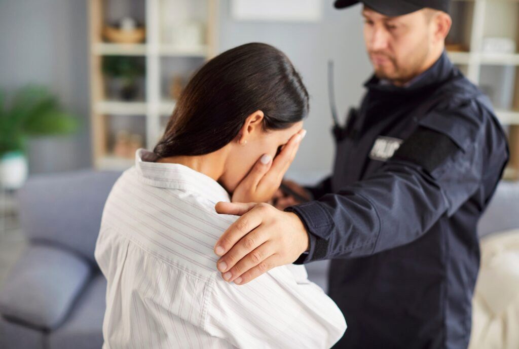 A Person Cries With a Security Guard's Hand on Their Shoulder Indoors — Bradley Solicitors in Larrakeyah, NT