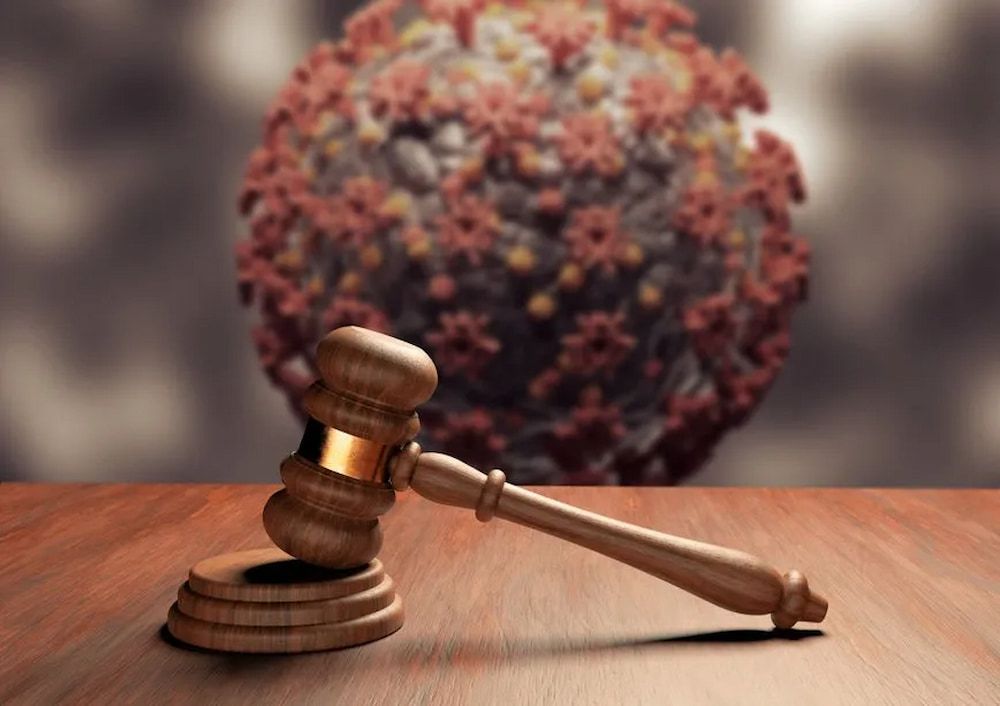 Wooden Gavel and Sound Block in Front of a Blurred Covid-19 Virus Model — Bradley Solicitors in Larrakeyah, NT