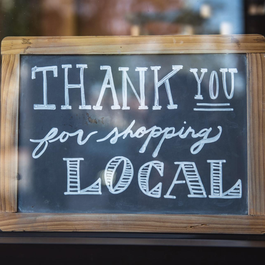 chalkboard sign in window that reads Thank you for shopping local