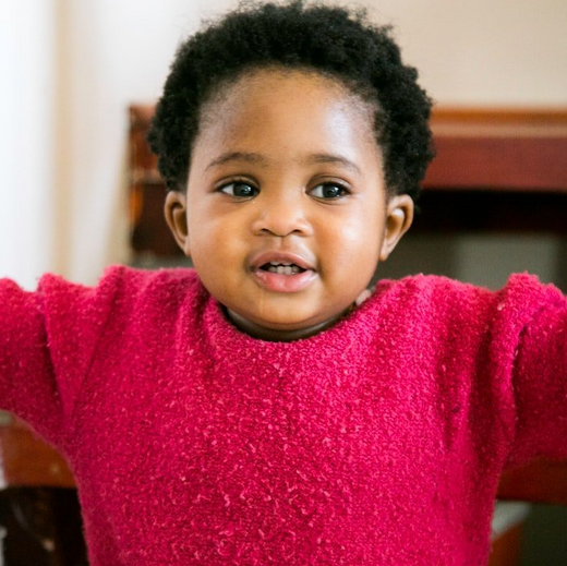 young toddler boy with red sweater and arms open wide