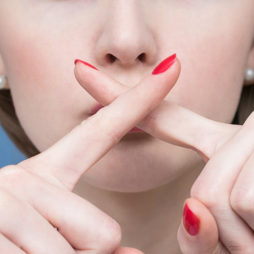 woman with fingers creating an X over her mouth