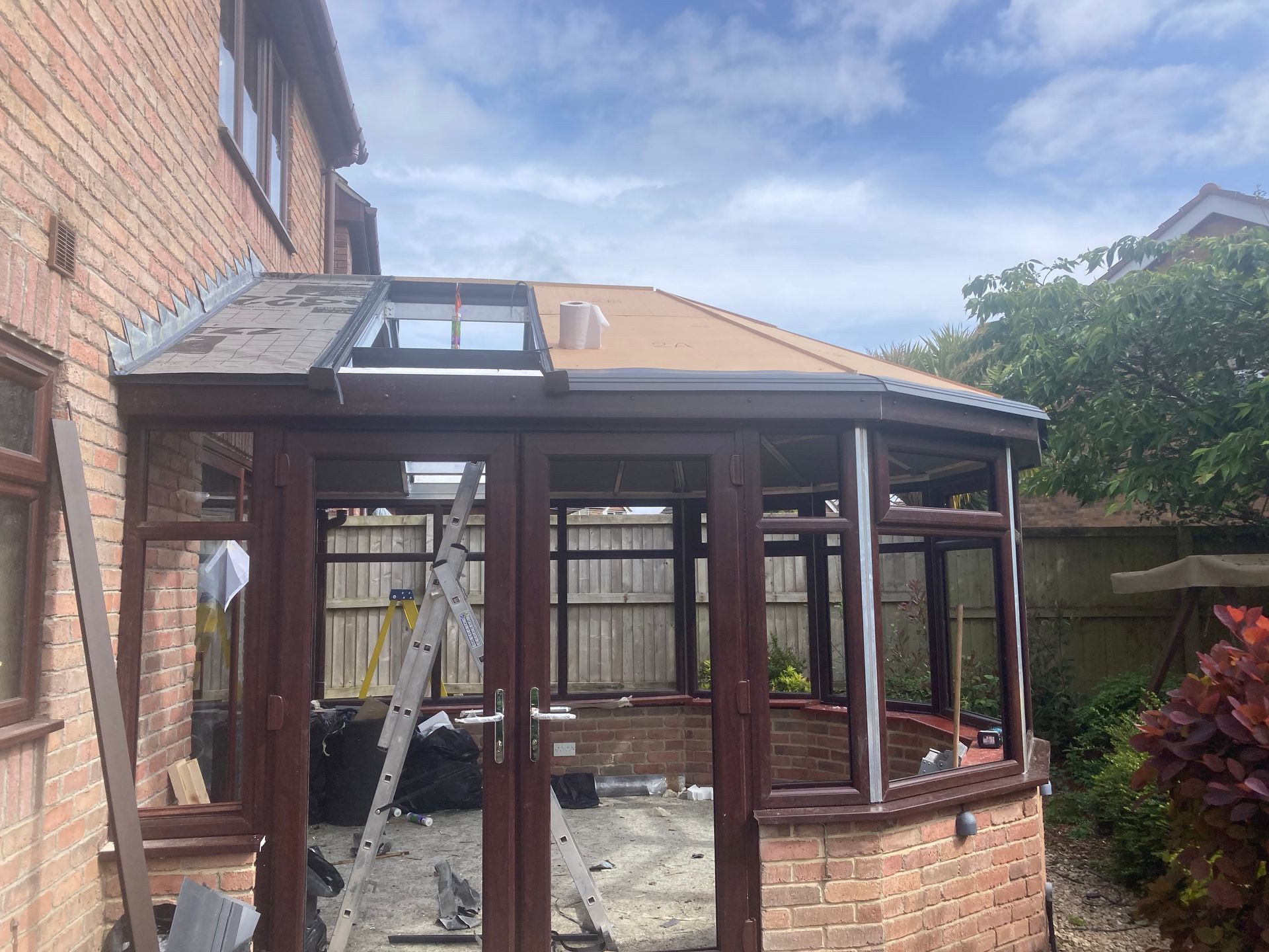 A conservatory is being built on the side of a brick house.