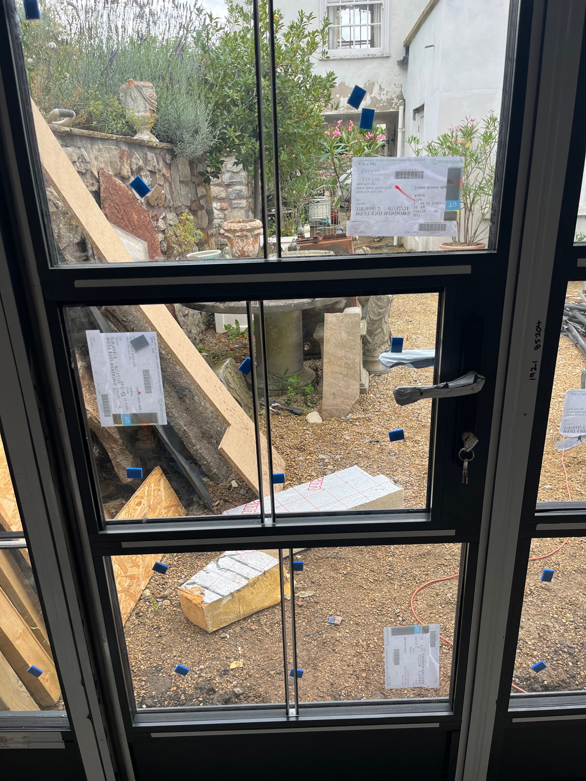 A window with a view of a garden and a house in the background.