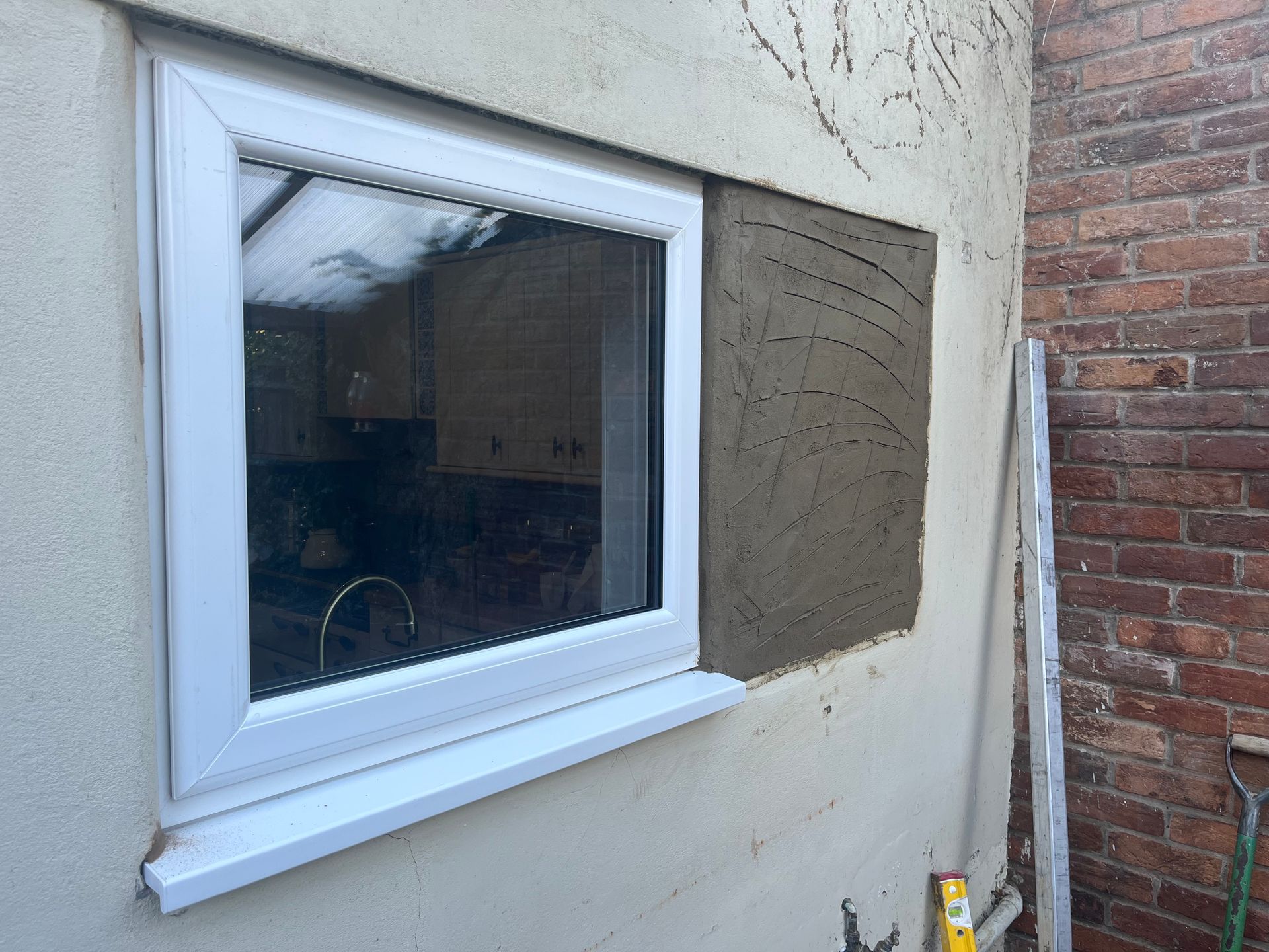 A white window is being installed on a brick wall.