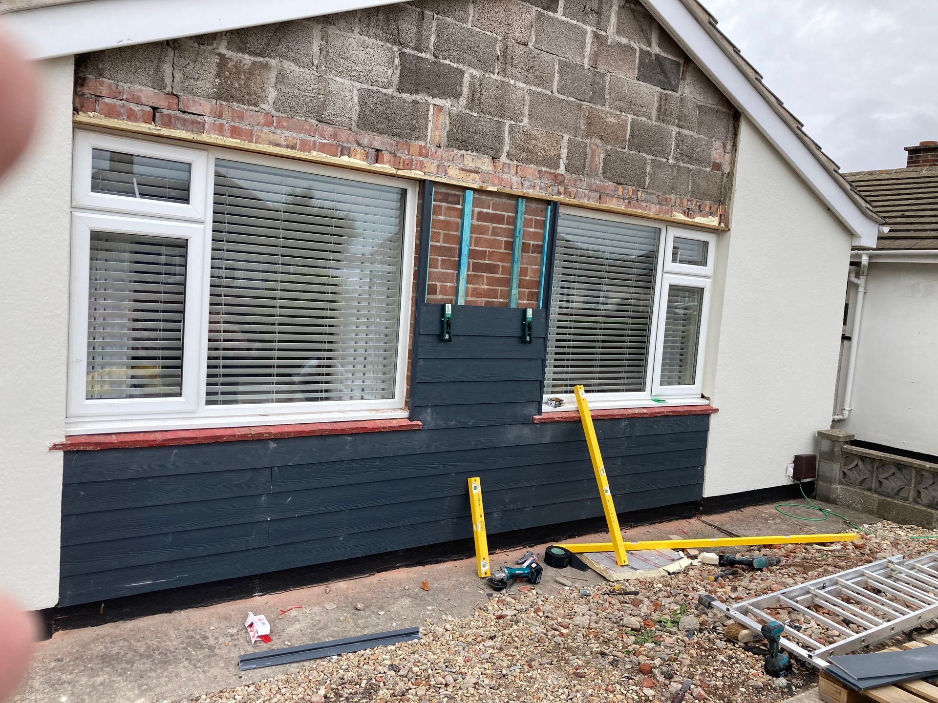 A person is standing in front of a house that is being remodeled.