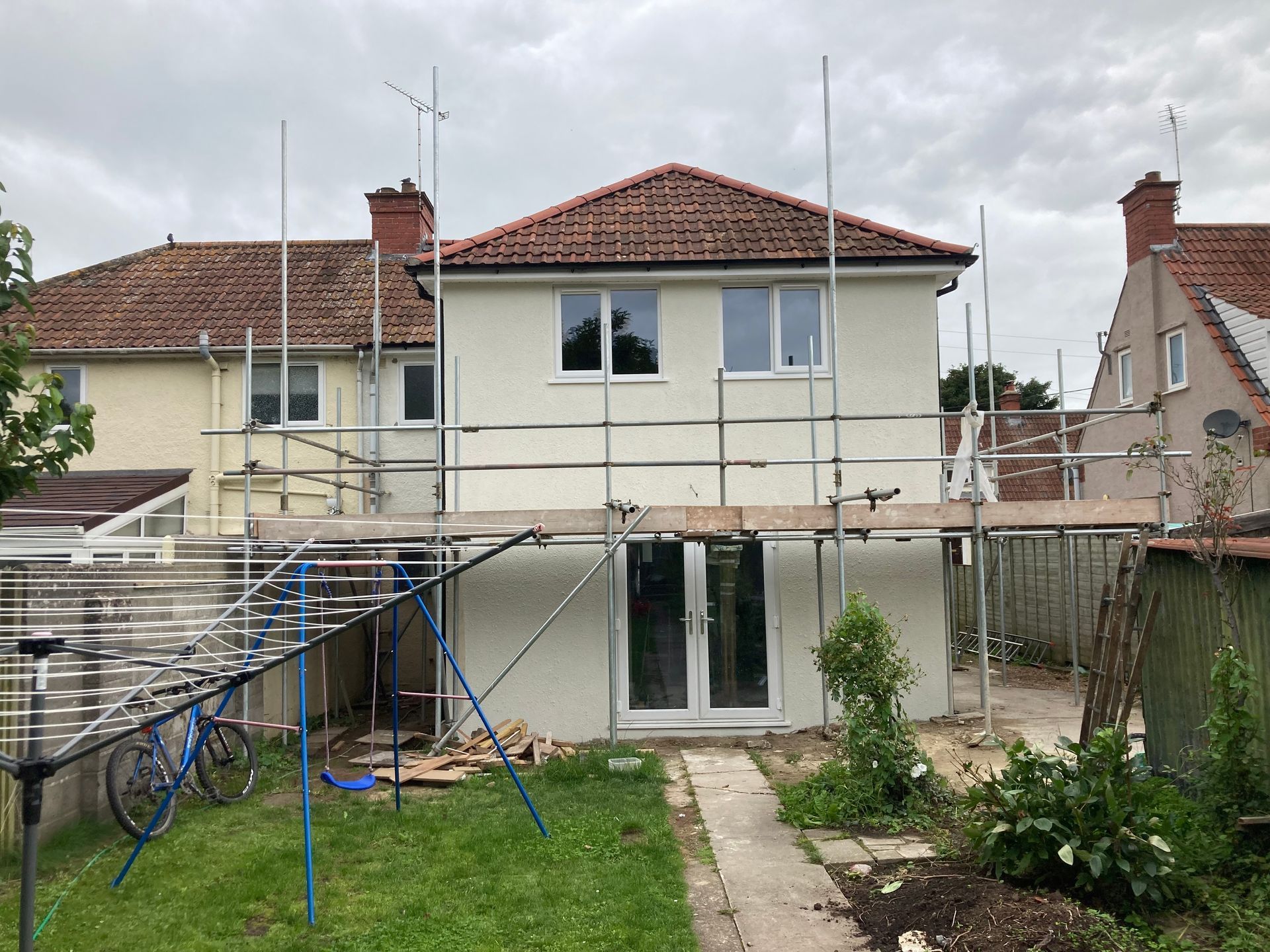 A house with scaffolding around it and a bicycle parked in front of it.