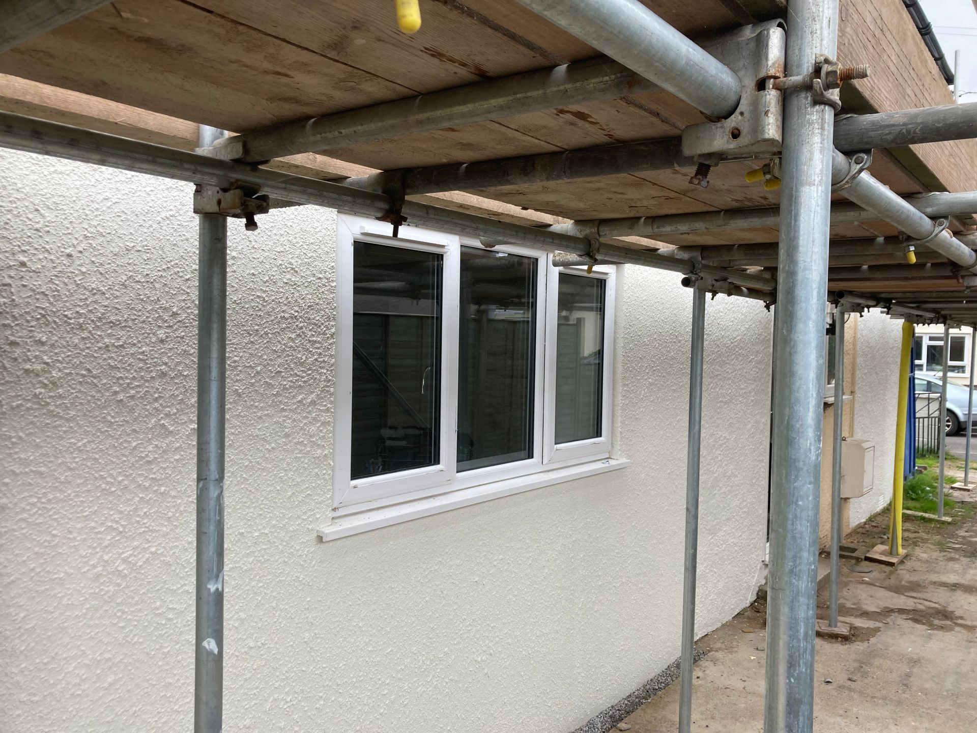 A white building with scaffolding around it and a window.