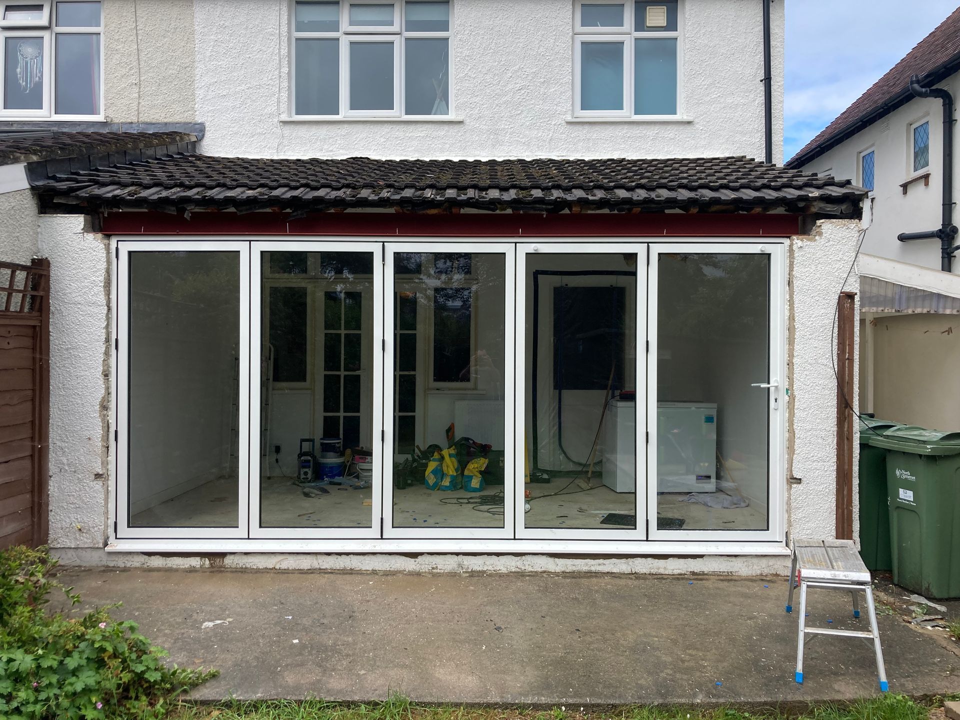 A house with a lot of windows and a ladder in front of it.