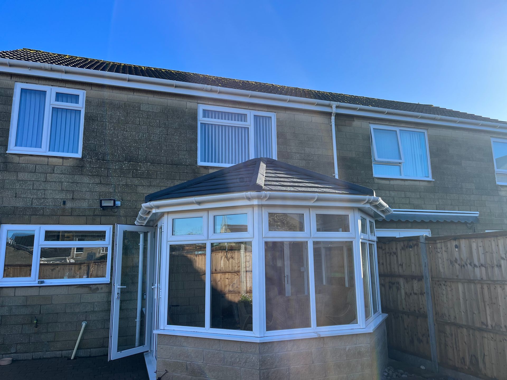 A house with a conservatory and a blue sky in the background