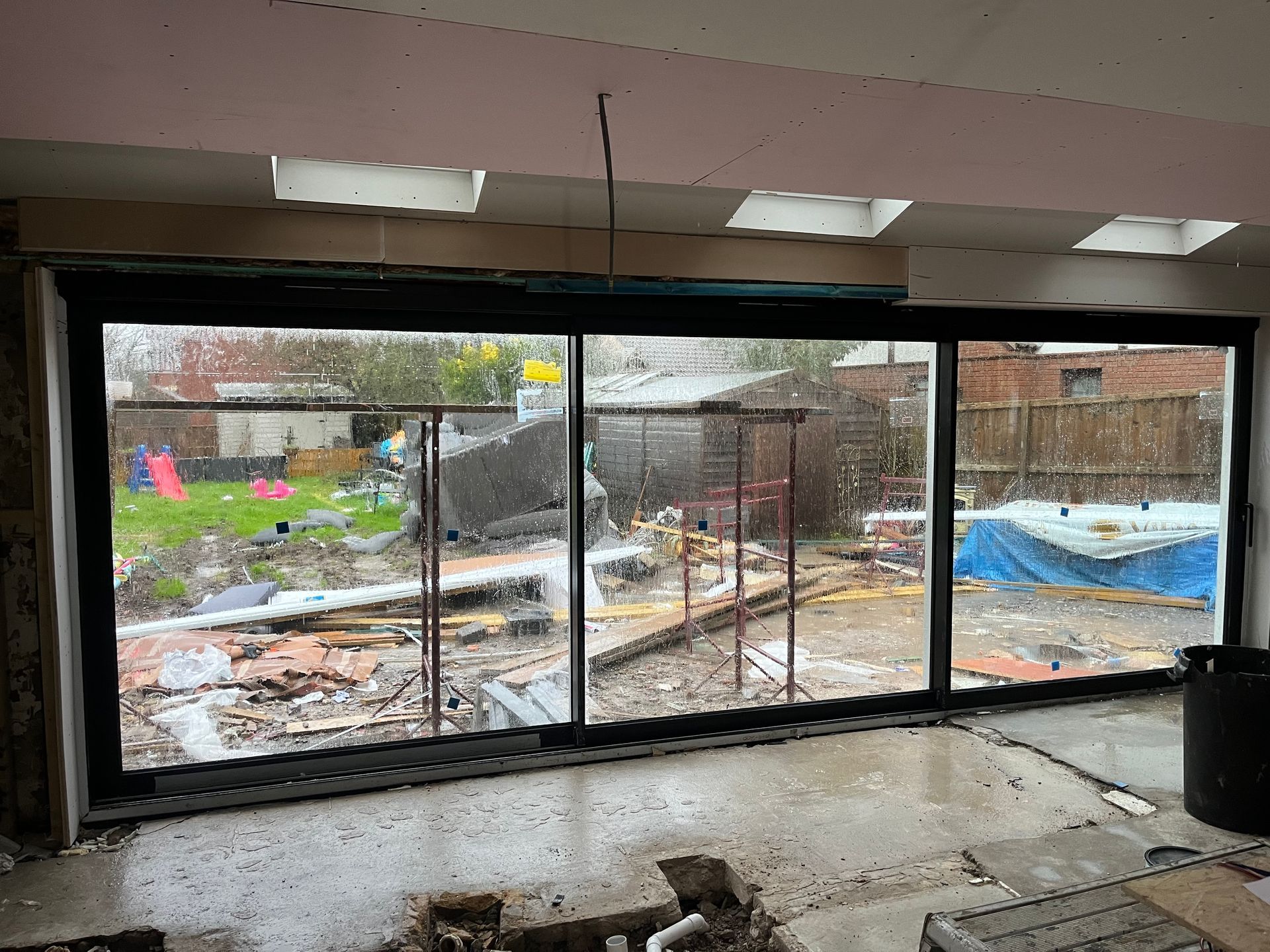 A room with a lot of windows and a view of a garden.