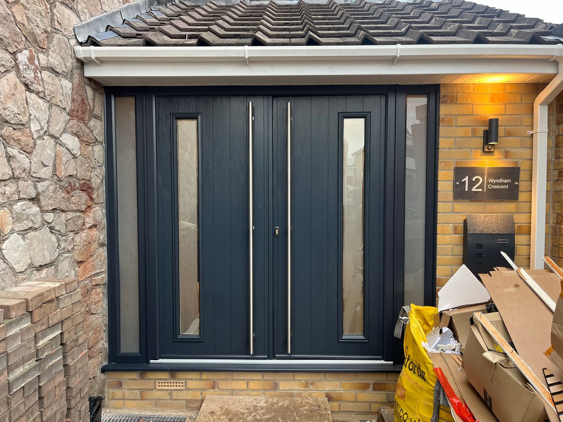 A house with a black front door and a yellow bag of cardboard.