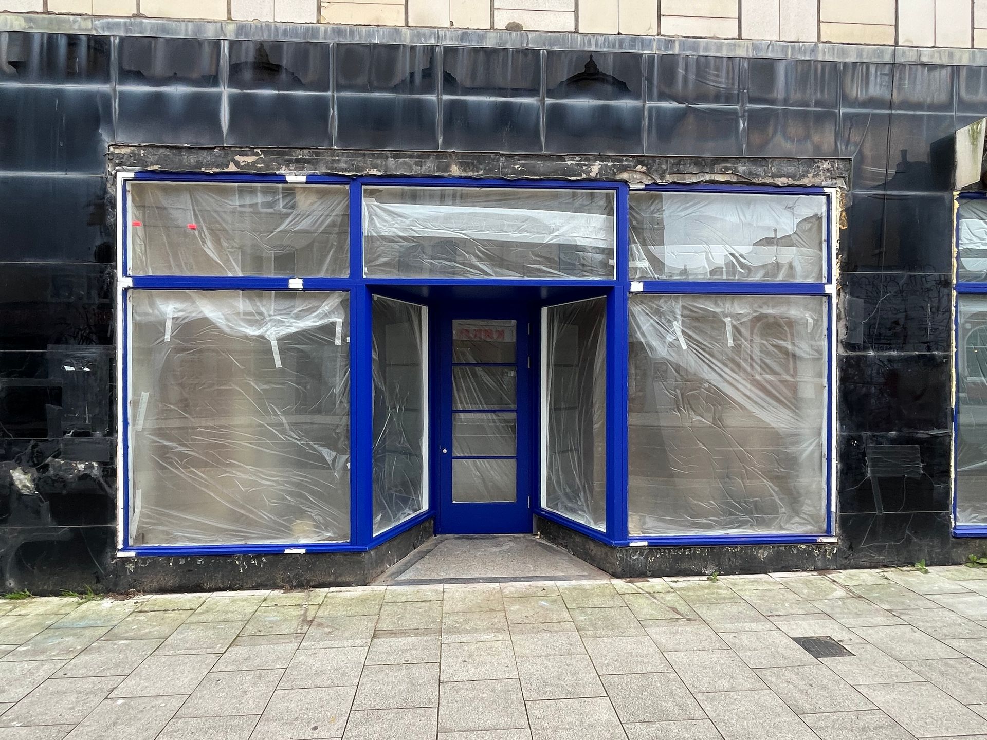 An empty store front with a blue door and windows