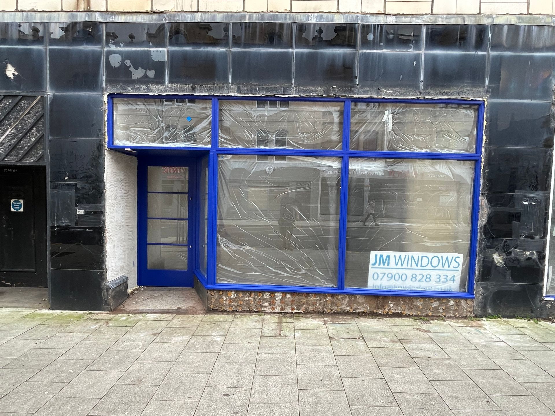 An empty store front with a sign that says jm windows