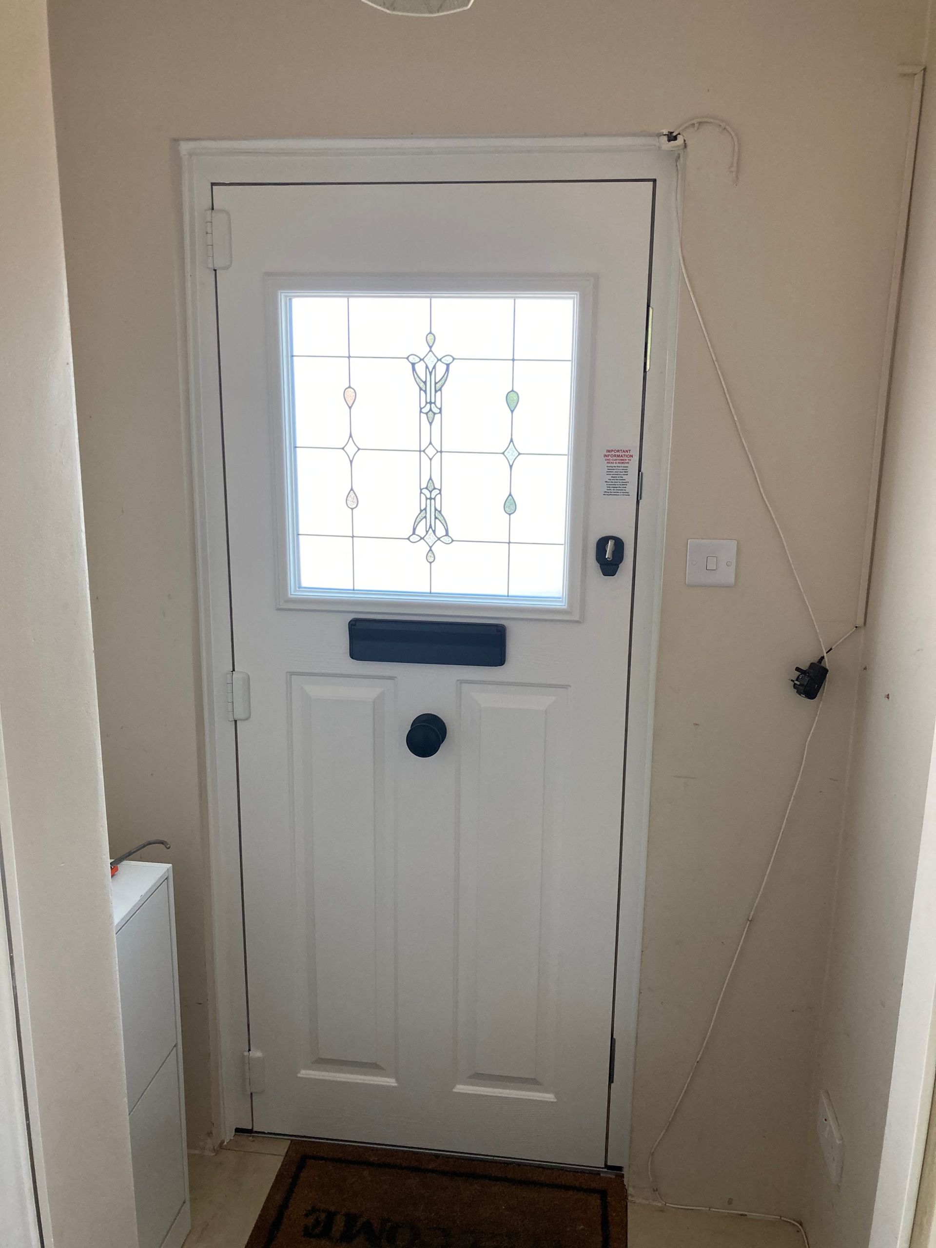 A white door with a window and a welcome mat in a hallway.