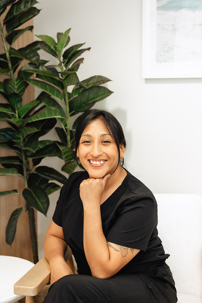 Smiling Asian woman in black scrubs poses outdoors.