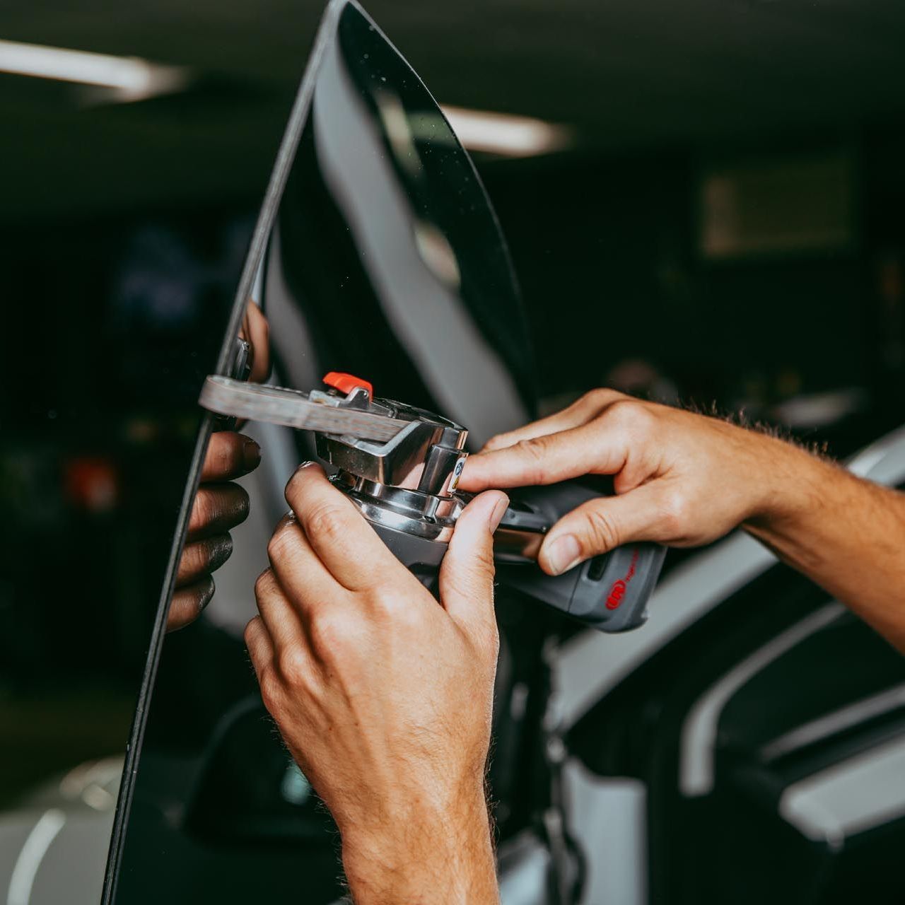 A person is installing a windshield on a car